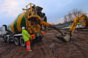 Cement Mixer Pouring Concrete in Excavator Trenching Bucket